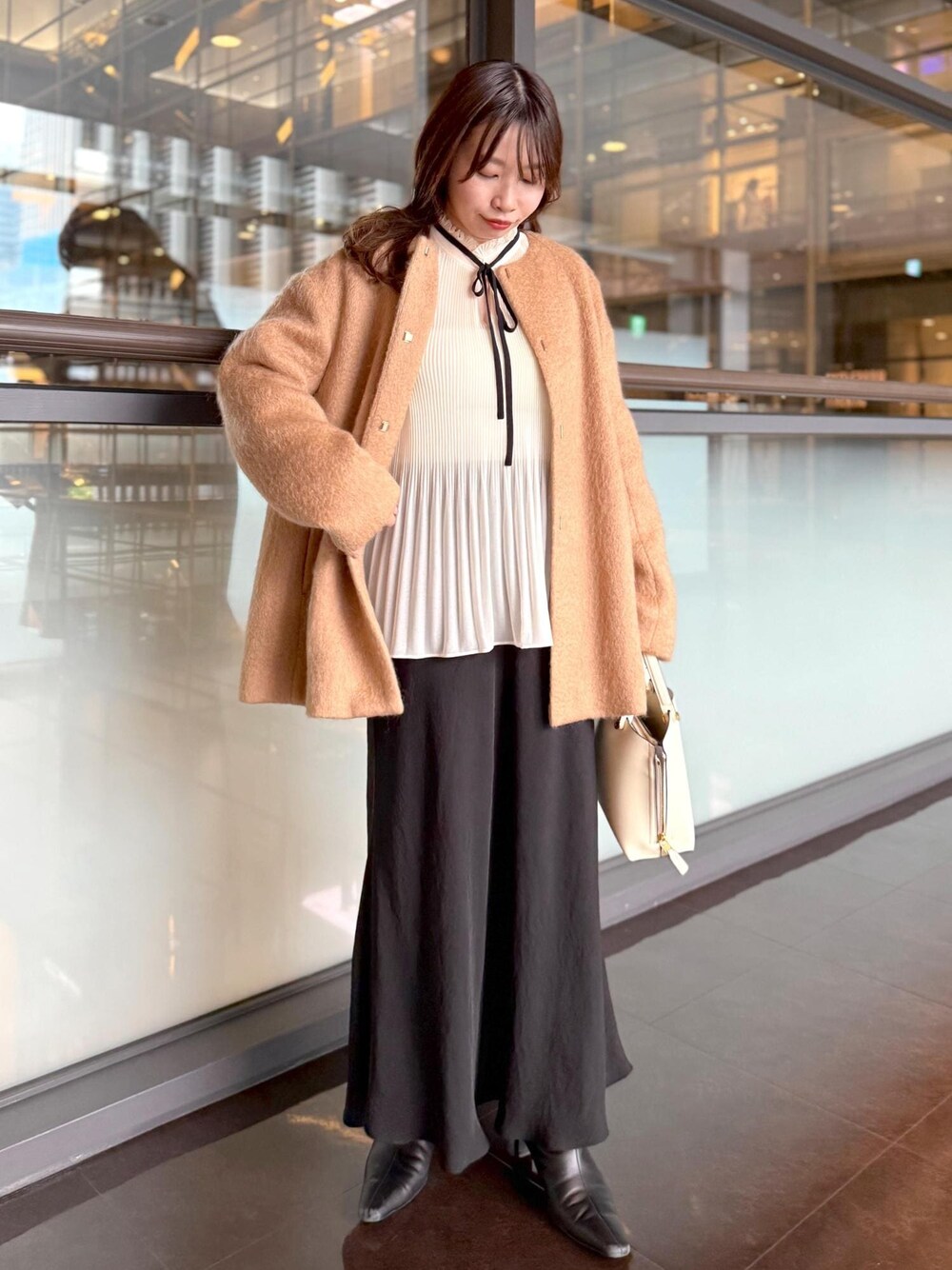 ホワイト系のハンドバッグ、ブラック系のスカート、ホワイト系のシャツ/ブラウスを着用したレディースの秋コーディネートの1枚目の写真