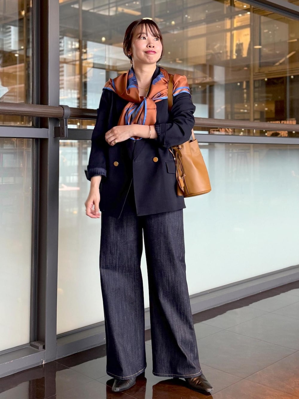 イエロー系のハンドバッグ、ブルー系のデニムパンツ、ホワイト系のカーディガン/ボレロを着用したレディースの秋コーディネートの1枚目の写真