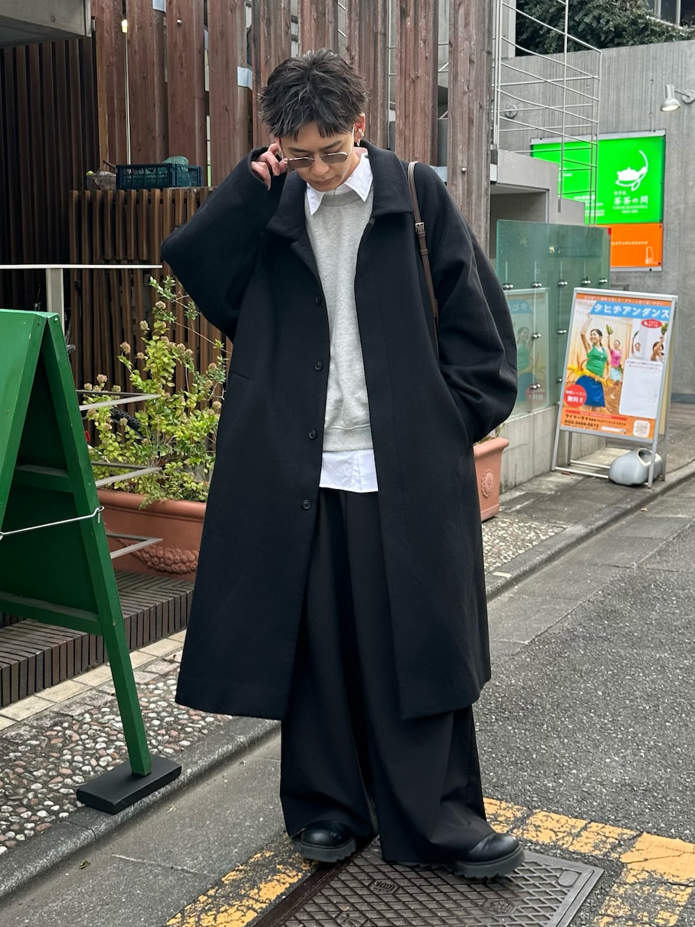 グレー系のスウェット、ブラック系のステンカラーコート、ブラック系のスラックスを着用したメンズの冬コーディネートの1枚目の写真