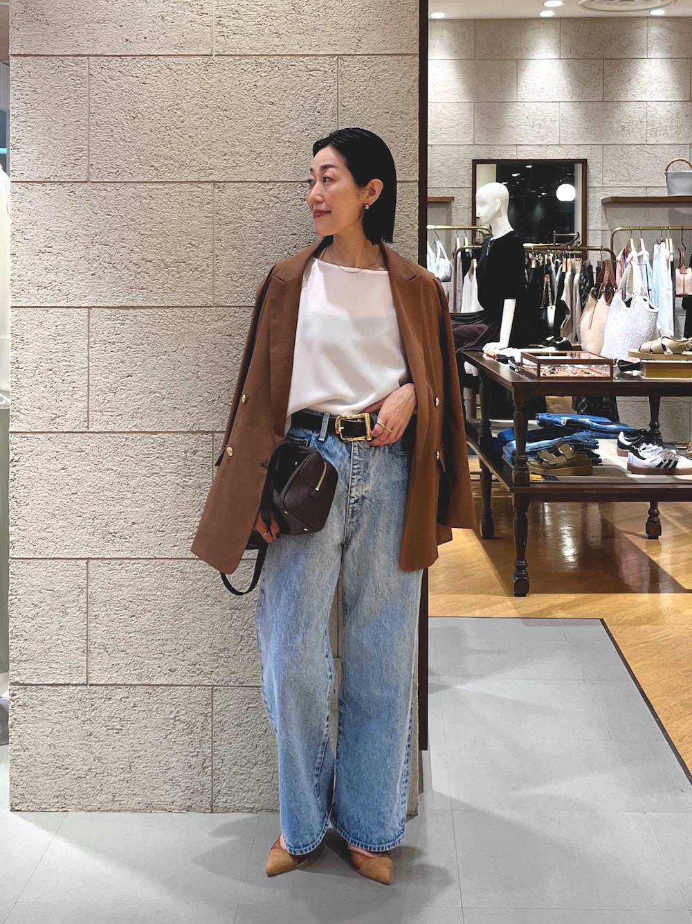 ブルー系のデニムパンツ、ブラウン系のパンプス、ブラウン系のショルダーバッグを着用したレディースの夏コーディネートの1枚目の写真