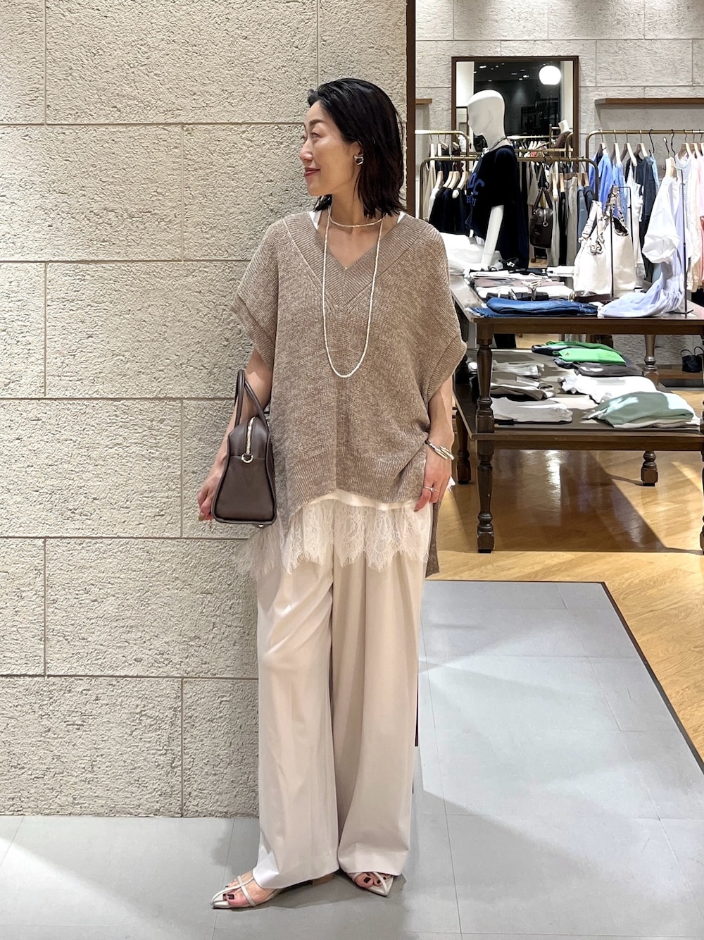 ベージュ系のサンダル、ブラウン系のボストンバッグ、ベージュ系のスラックスを着用したレディースの夏コーディネートの1枚目の写真