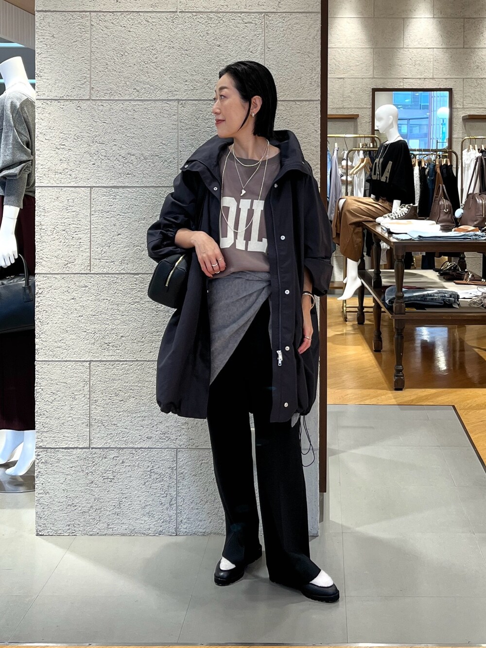 ブラック系のショルダーバッグ、ブラウン系のスウェット、グレー系のその他アウターを着用したレディースの秋コーディネートの1枚目の写真