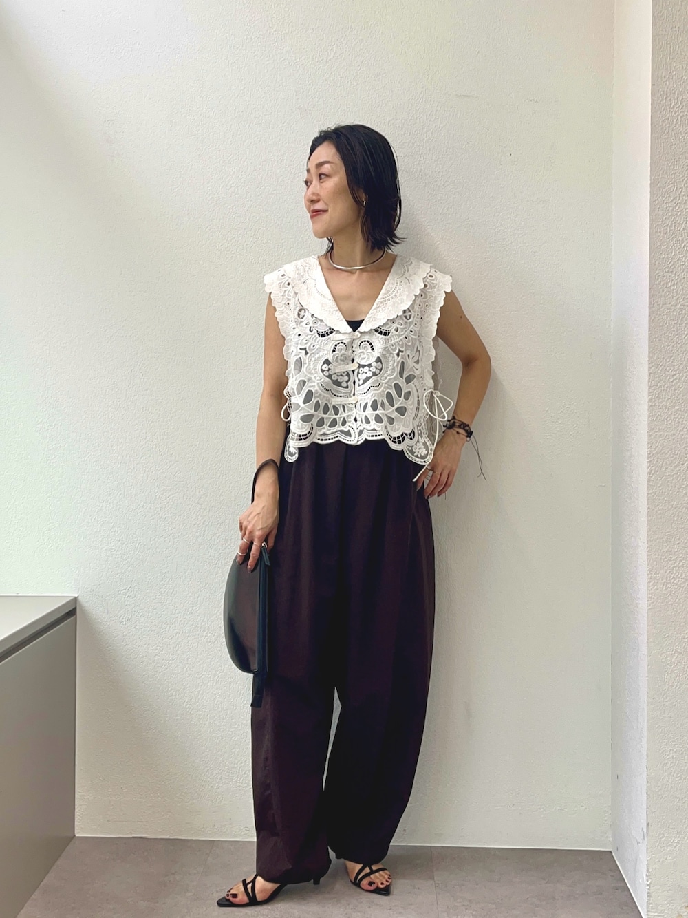 ブラウン系のその他パンツ、ブラウン系のサンダル、ホワイト系のベストを着用したレディースの夏コーディネートの1枚目の写真