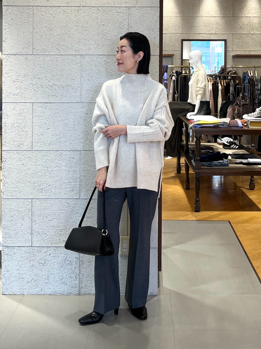 ホワイト系のニット/セーター、ブラック系のハンドバッグ、グレー系のその他パンツを着用したレディースの秋コーディネートの1枚目の写真