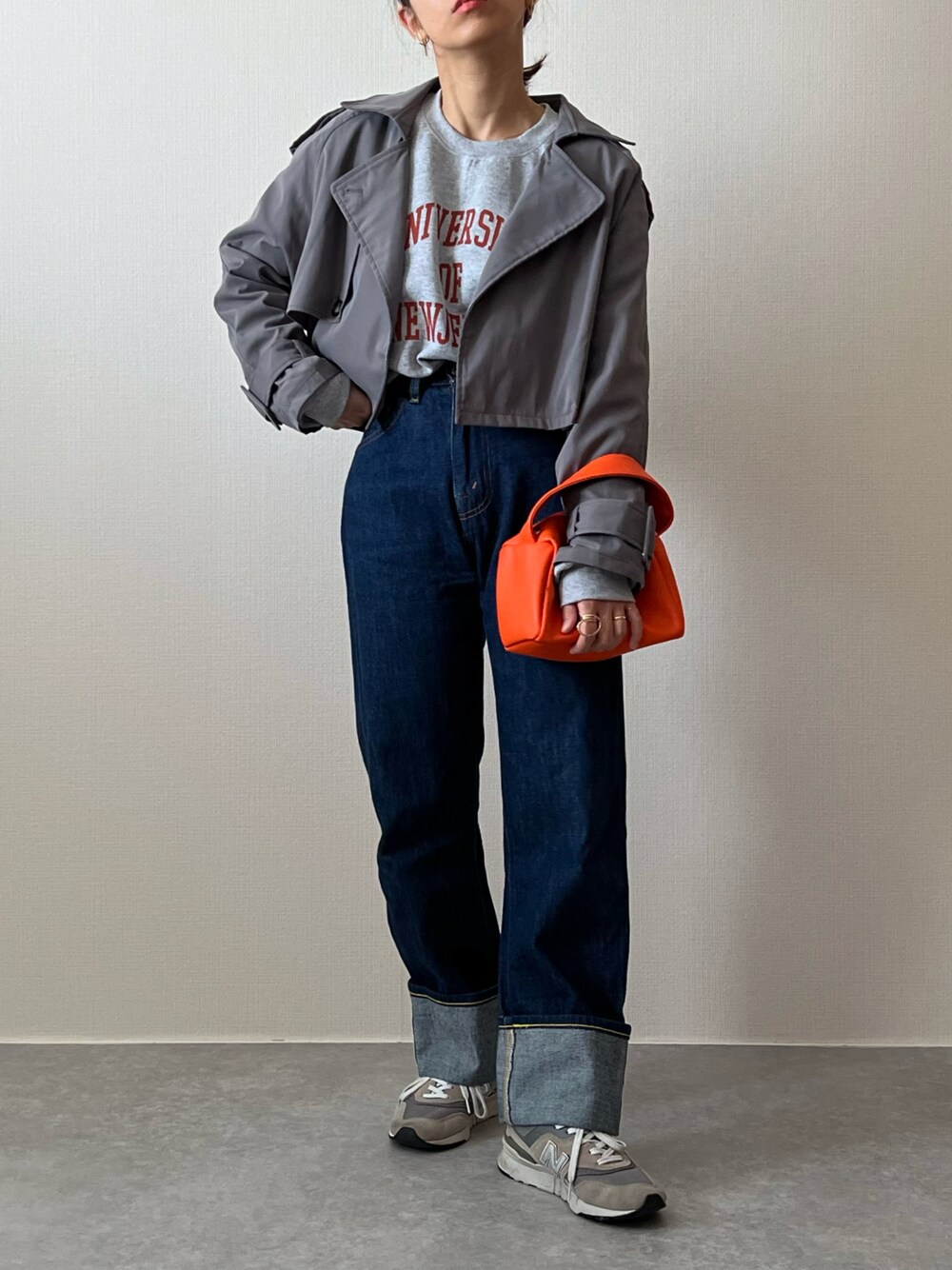 グレー系のスウェット、ブルー系のデニムパンツ、グレー系のスニーカーを着用したレディースの秋コーディネートの1枚目の写真