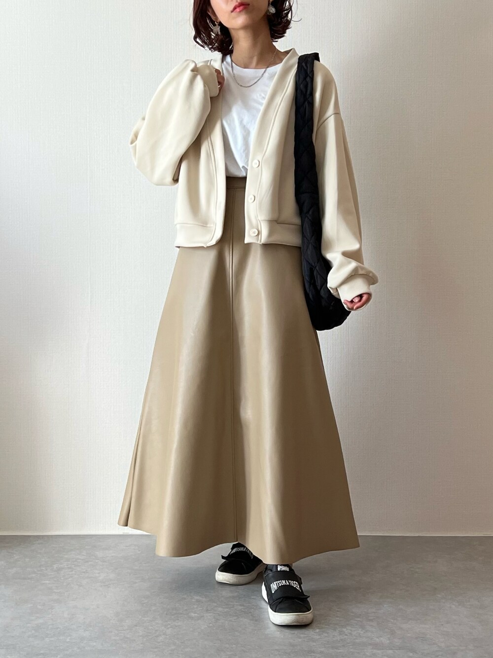 ベージュ系のカーディガン/ボレロ、ホワイト系のTシャツ/カットソー、ブラック系のショルダーバッグを着用したレディースの秋コーディネートの1枚目の写真