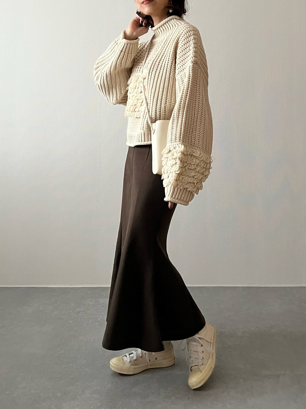 ホワイト系のニット/セーター、ホワイト系のショルダーバッグ、ホワイト系のスニーカーを着用したレディースの秋コーディネートの1枚目の写真