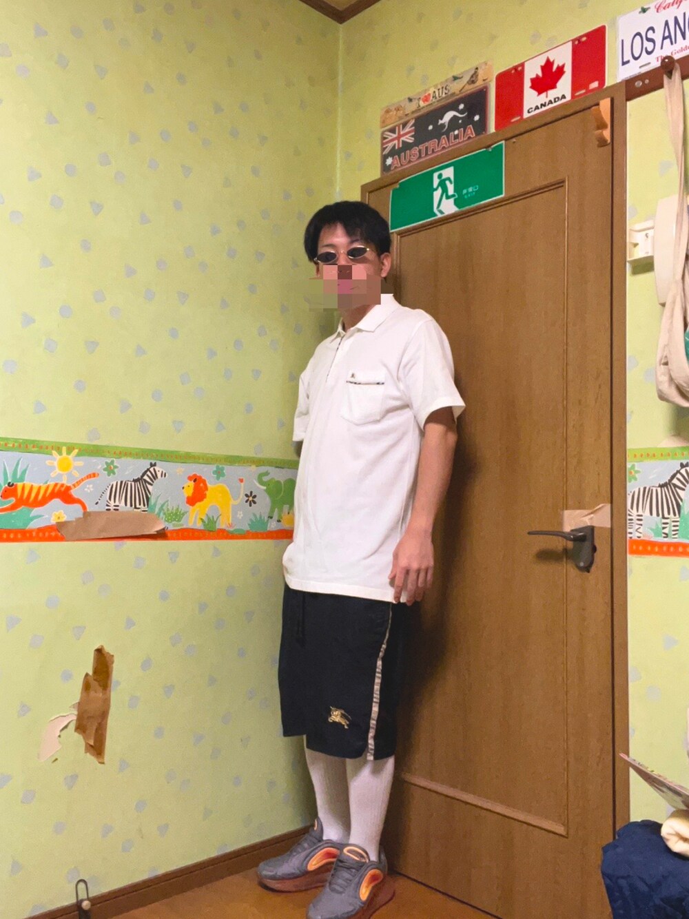 ホワイト系のポロシャツ、ブラック系のパンツ、シルバー系のスニーカーを着用したメンズの夏コーディネートの1枚目の写真