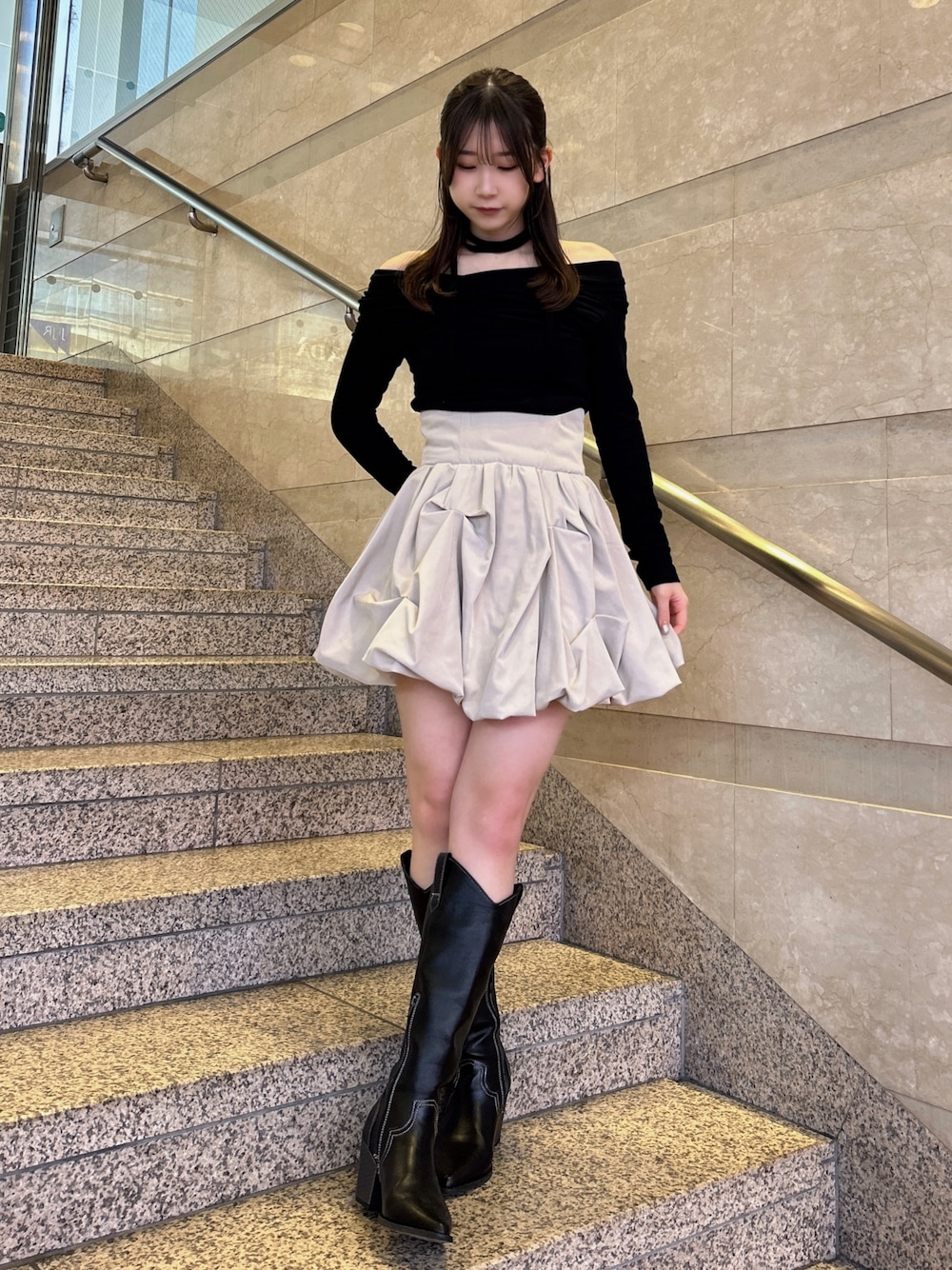 ブラック系のTシャツ/カットソー、ベージュ系のスカート、その他のブーツを着用したレディースの冬コーディネートの1枚目の写真