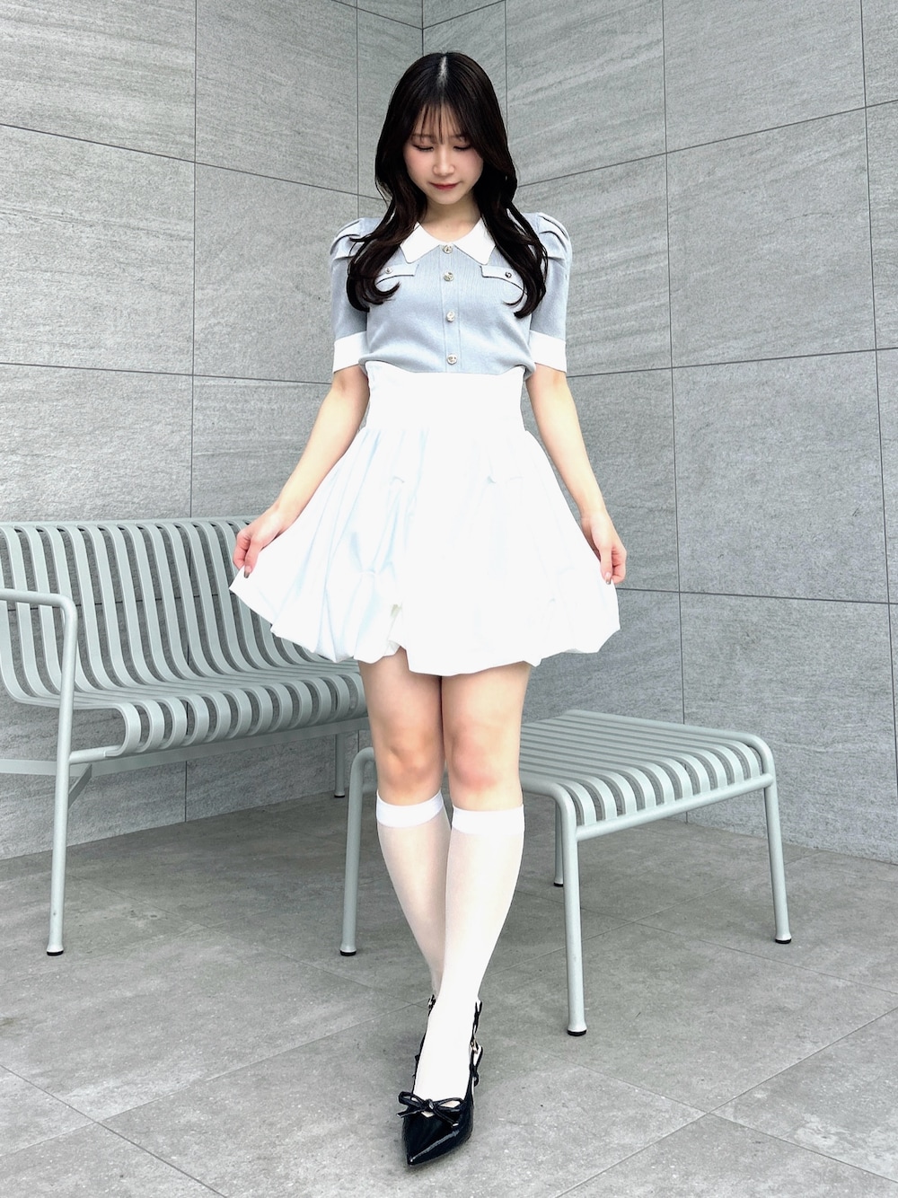 グレー系のニット/セーター、ホワイト系のスカートを着用したレディースの冬コーディネートの1枚目の写真