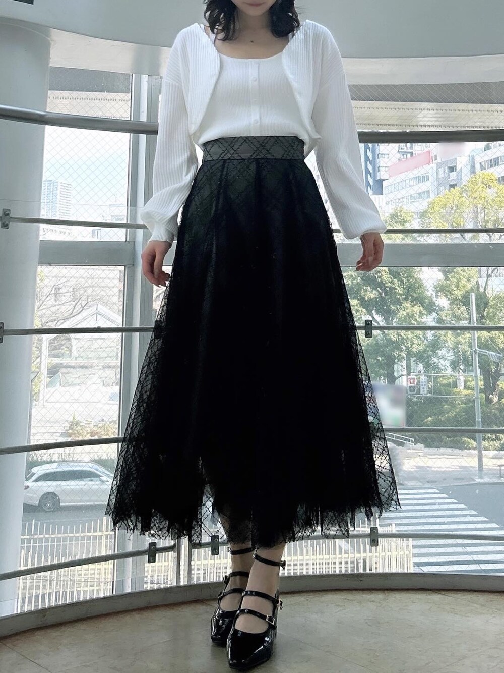 ホワイト系のアンサンブル、ブラック系のスカート、ブラック系のパンプスを着用したレディースの春コーディネートの1枚目の写真