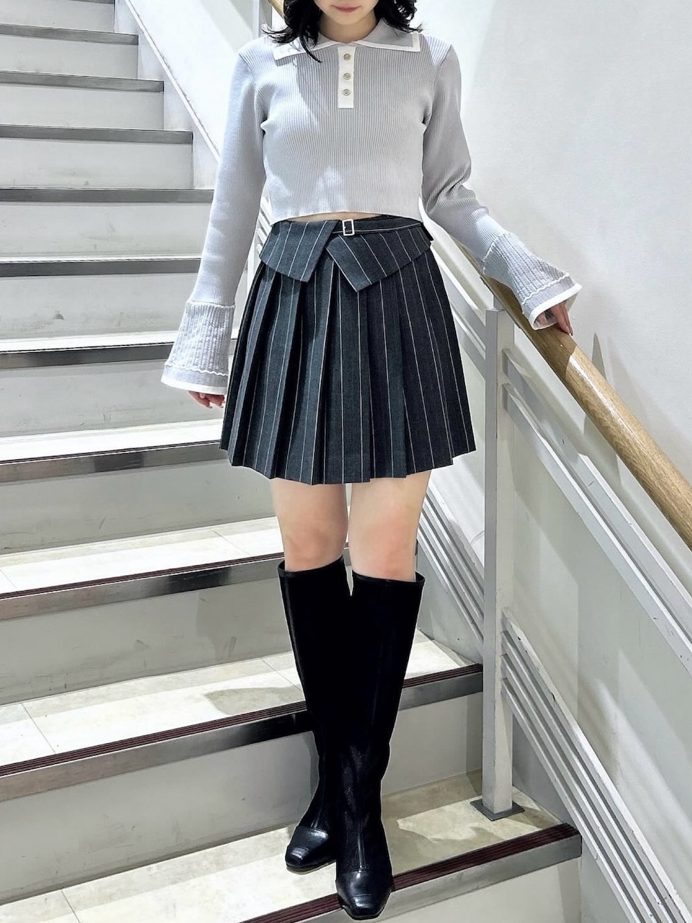 グレー系のニット/セーター、グレー系のスカート、ブラック系のブーツを着用したレディースの冬コーディネートの1枚目の写真