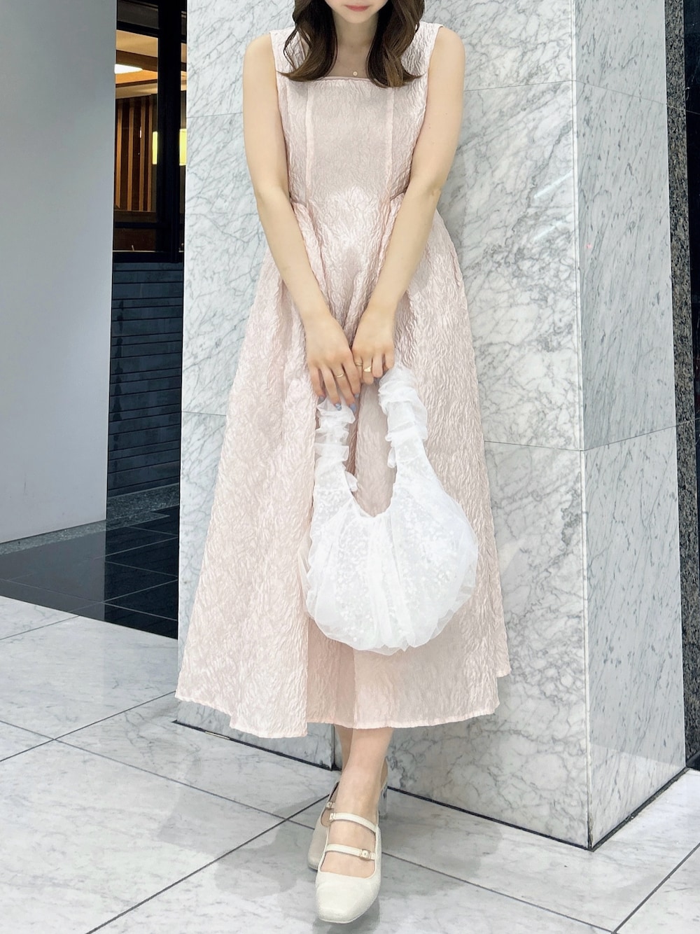 ホワイト系のパンプス、ホワイト系のハンドバッグ、ピンク系のドレスを着用したレディースの夏コーディネートの1枚目の写真