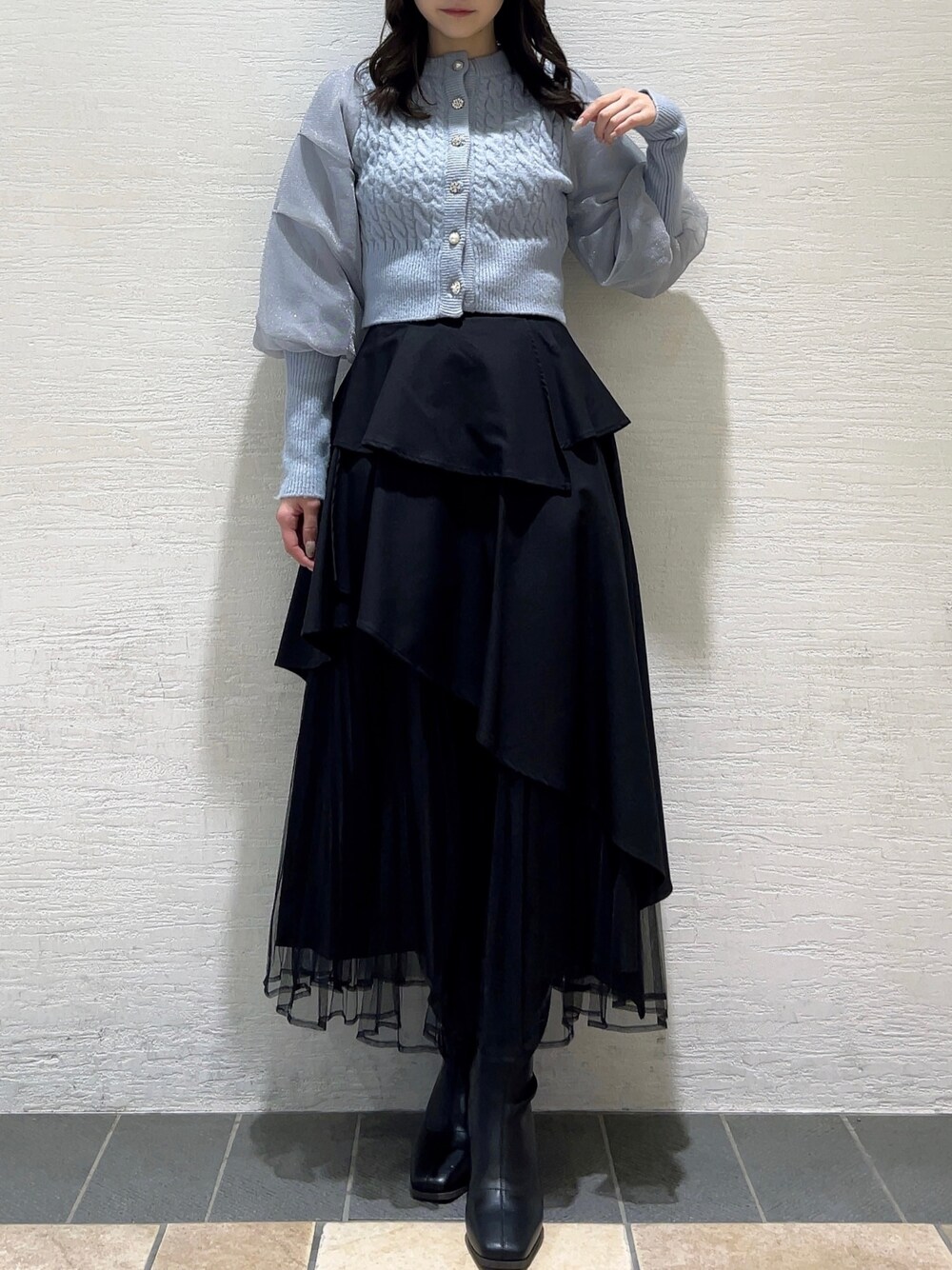 ブルー系のカーディガン/ボレロ、ブラック系のスカート、ブラック系のブーツを着用したレディースの冬コーディネートの1枚目の写真