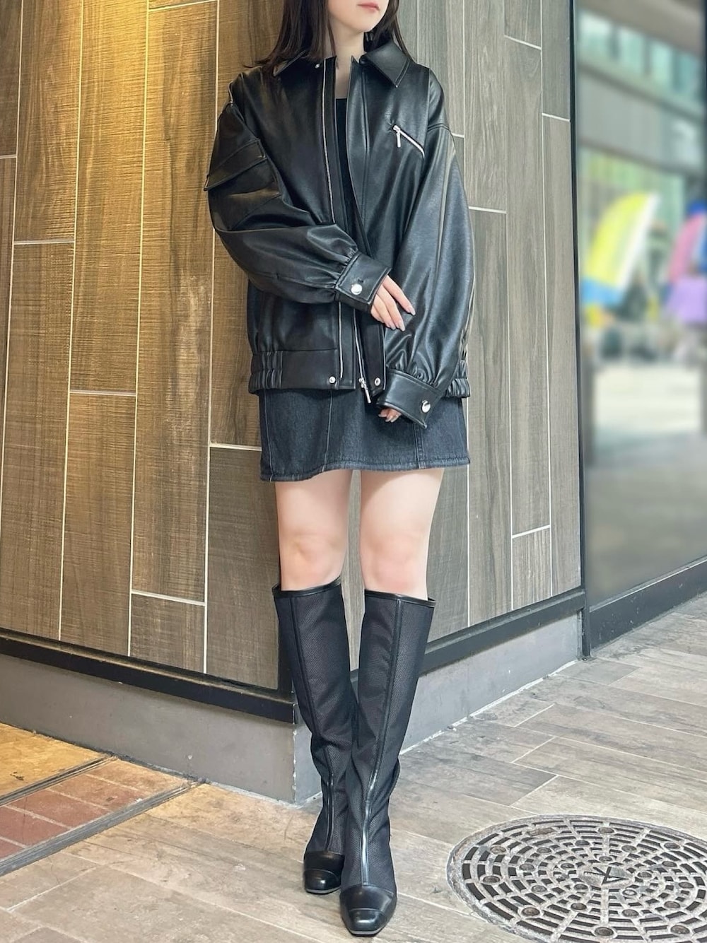 ブラック系のブルゾン、ブラック系のワンピース、ブラック系のブーツを着用したレディースの春コーディネートの1枚目の写真