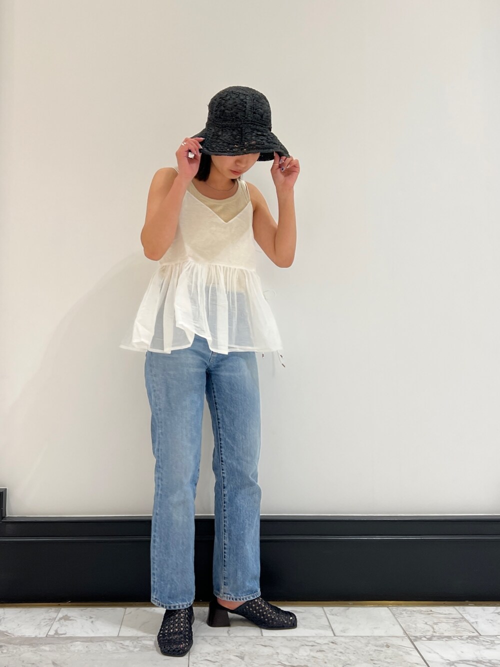 ホワイト系のシャツ/ブラウス、ベージュ系のタンクトップ、ブルー系のデニムパンツを着用したレディースの春コーディネートの1枚目の写真