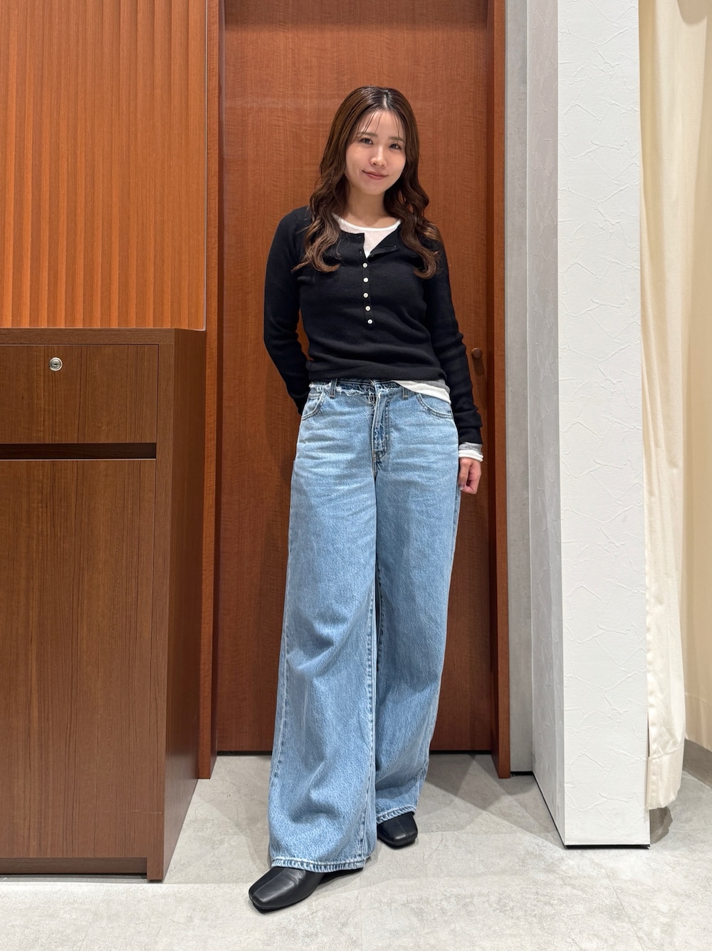ブルー系のデニムパンツ、ブラック系のニット/セーターを着用したレディースの秋コーディネートの1枚目の写真