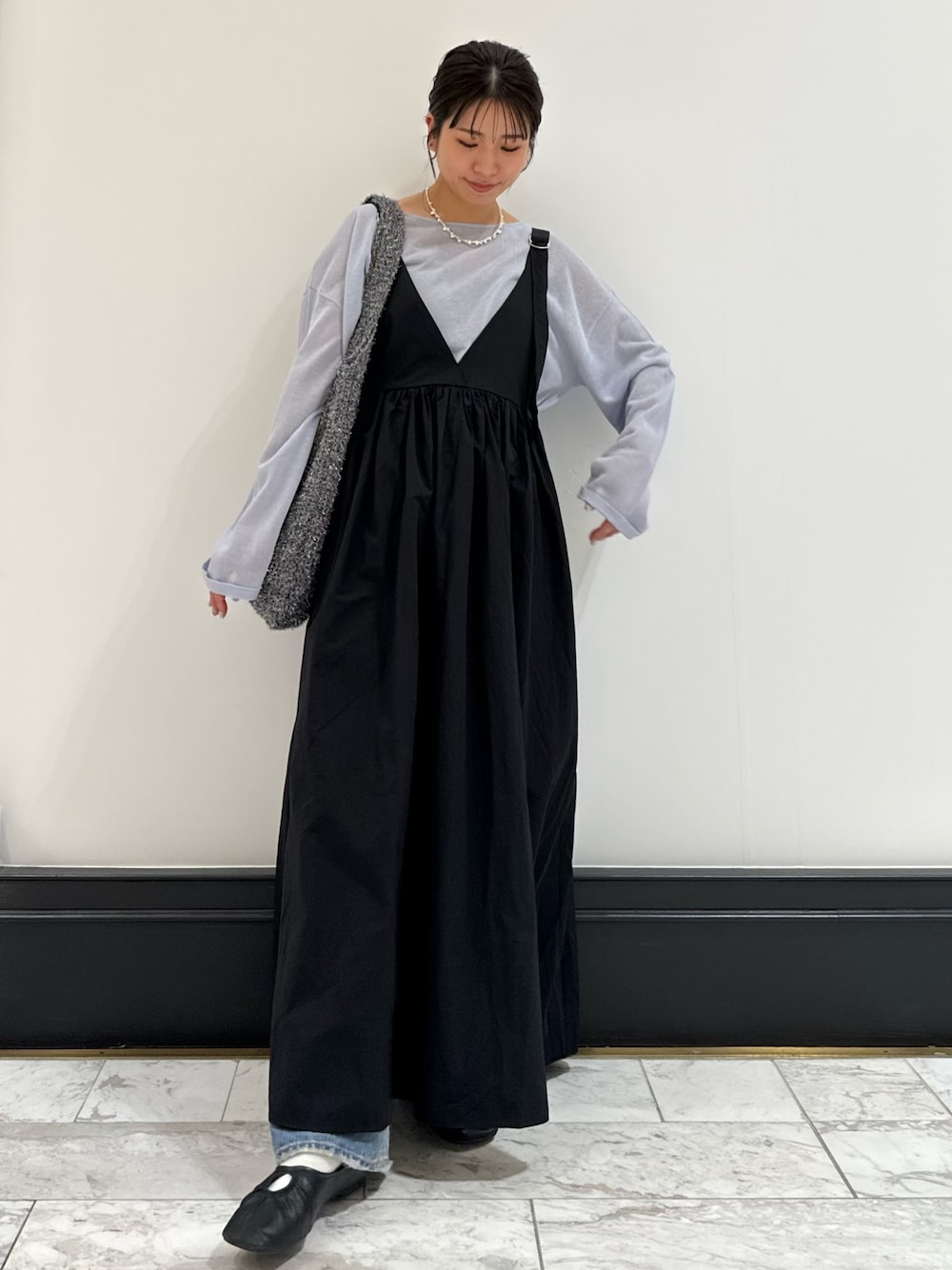 ブラック系のワンピース、ブルー系のニット/セーター、ブルー系のデニムパンツを着用したレディースの春コーディネートの1枚目の写真