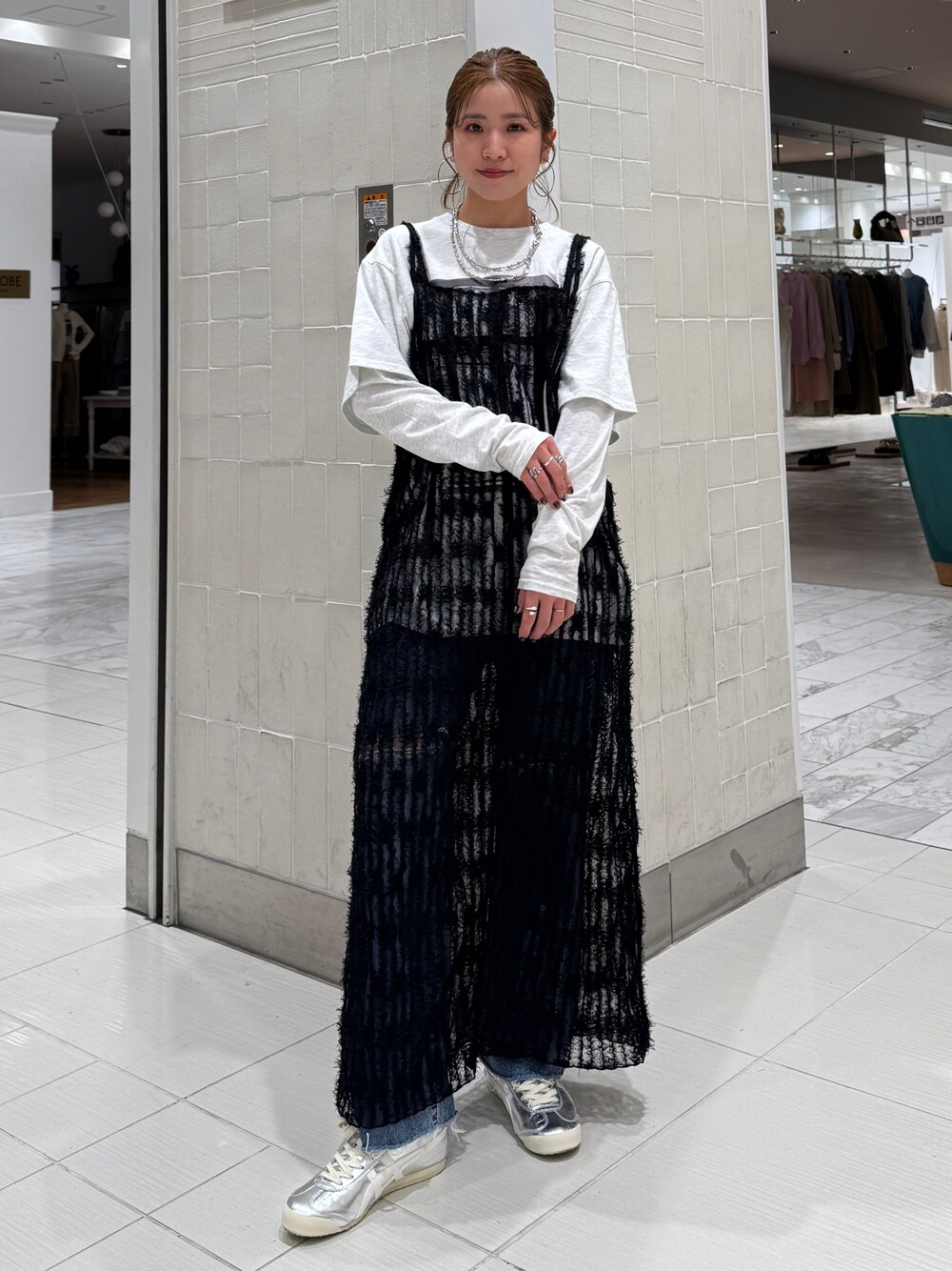 ブラック系のワンピース、グレー系のTシャツ/カットソー、ブルー系のデニムパンツを着用したレディースの春コーディネートの1枚目の写真