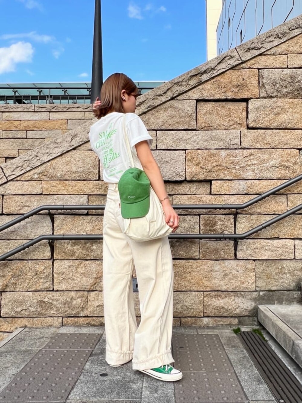 ホワイト系のデニムパンツ、ホワイト系のTシャツ/カットソー、グリーン系のキャップを着用したレディースの春コーディネートの1枚目の写真