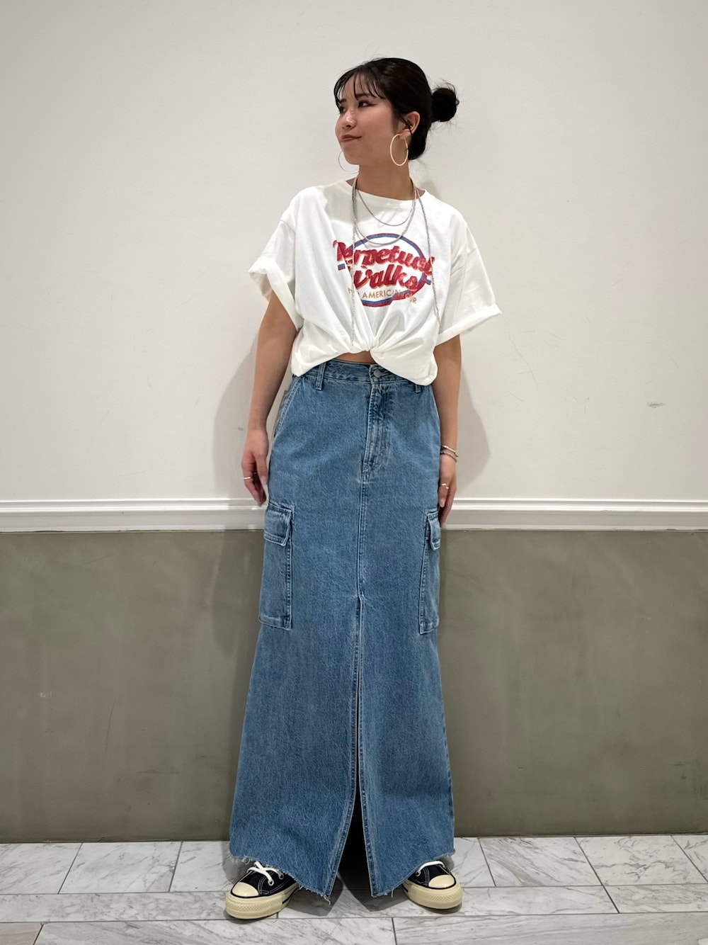 ブルー系のデニムスカート、ホワイト系のTシャツ/カットソー、ブルー系のスニーカーを着用したレディースの春コーディネートの1枚目の写真