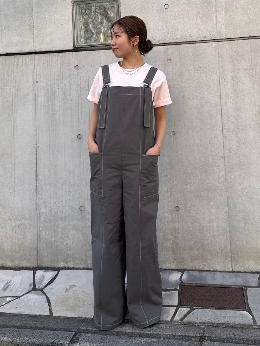 ピンク系のTシャツ/カットソー、ブラック系のサロペット/オーバーオール、ブラック系のサンダルを着用したレディースの春コーディネートの1枚目の写真