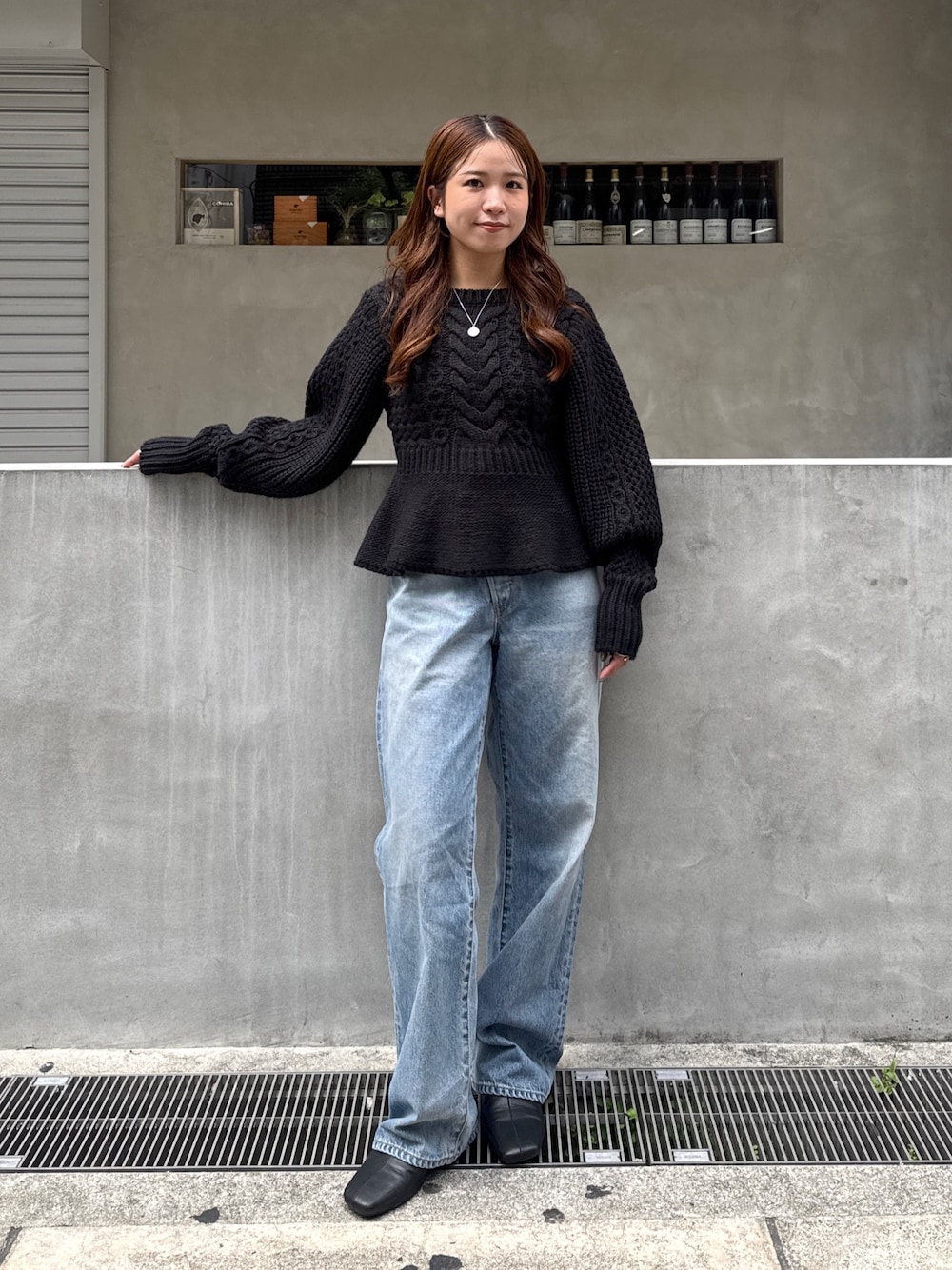 ブラック系のニット/セーター、ブルー系のデニムパンツ、ブラック系のサンダルを着用したレディースの秋コーディネートの1枚目の写真