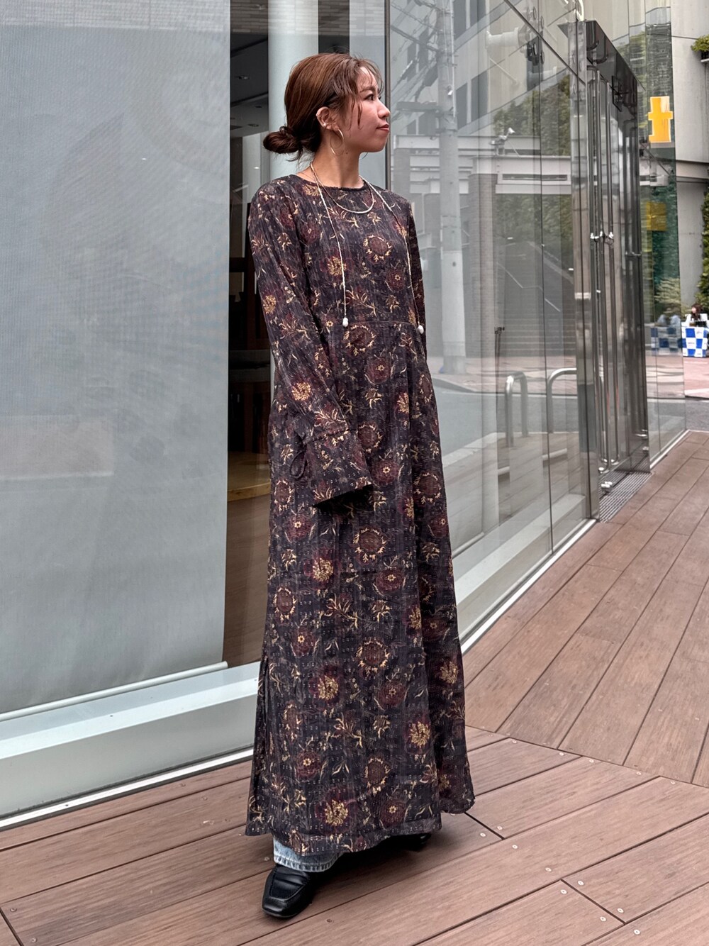 ブラック系のワンピース、ブルー系のデニムパンツ、ブラウン系のネックレスを着用したレディースの冬コーディネートの1枚目の写真