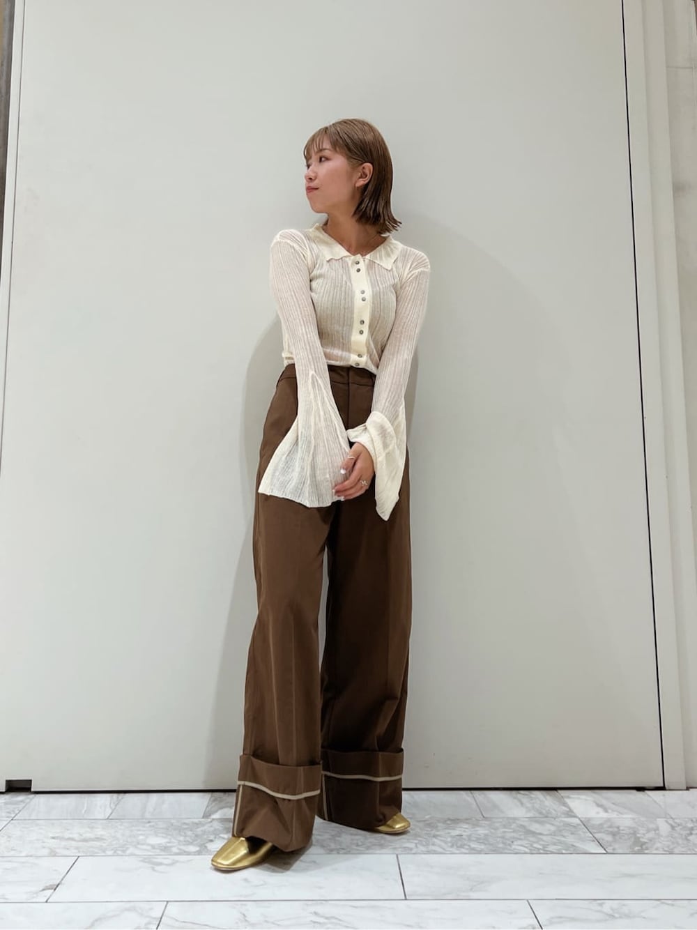 ブラウン系のチノパンツ、ゴールド系のパンプス、ホワイト系のカーディガン/ボレロを着用したレディースの夏コーディネートの1枚目の写真