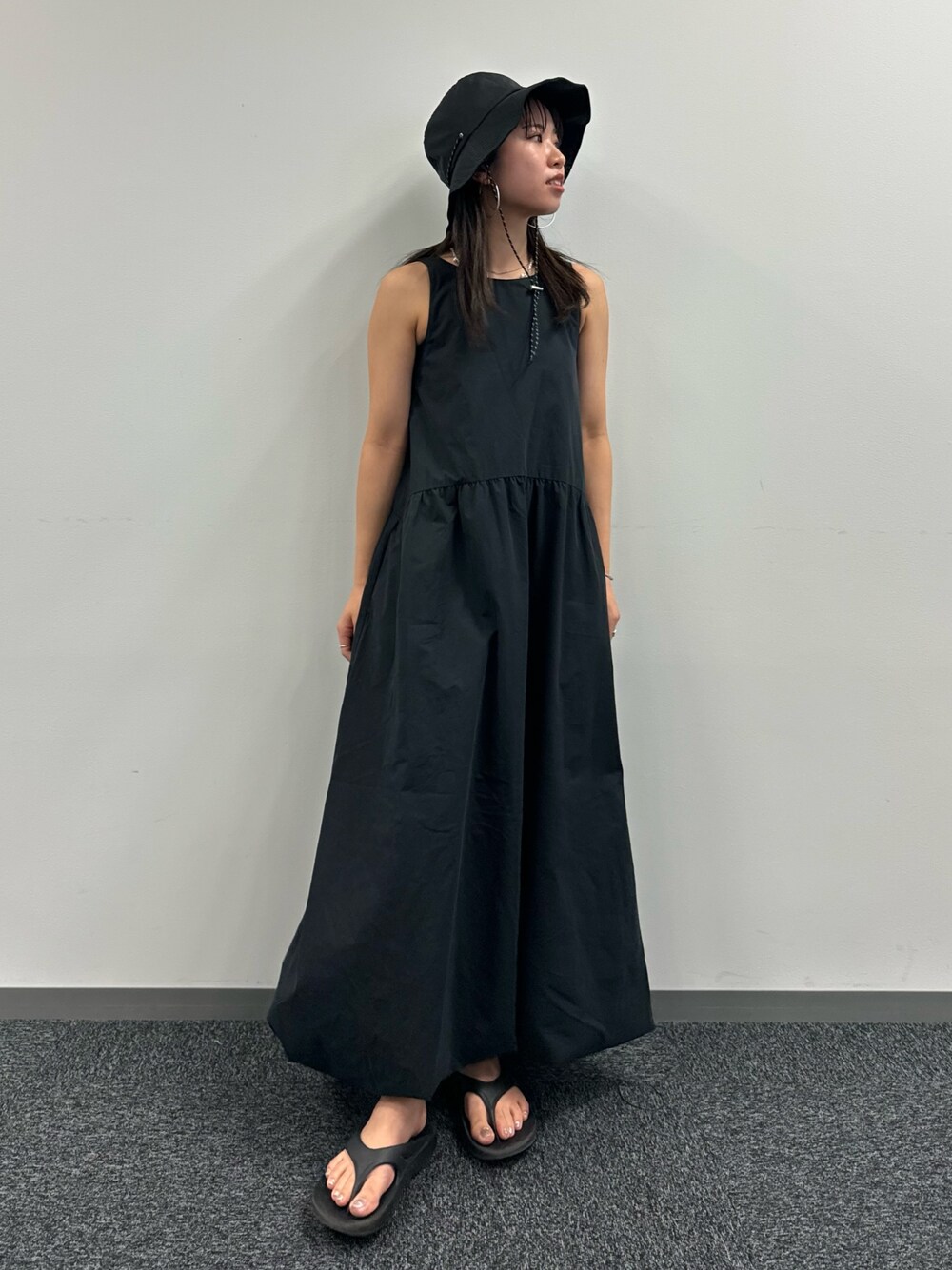 ブラック系のワンピース、ブラック系のハットを着用したレディースの春コーディネートの1枚目の写真