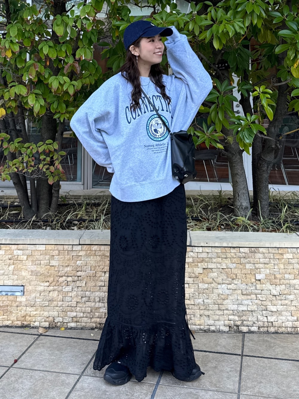 ブラック系のスカート、グレー系のスウェット、ブラック系のスニーカーを着用したレディースの冬コーディネートの1枚目の写真