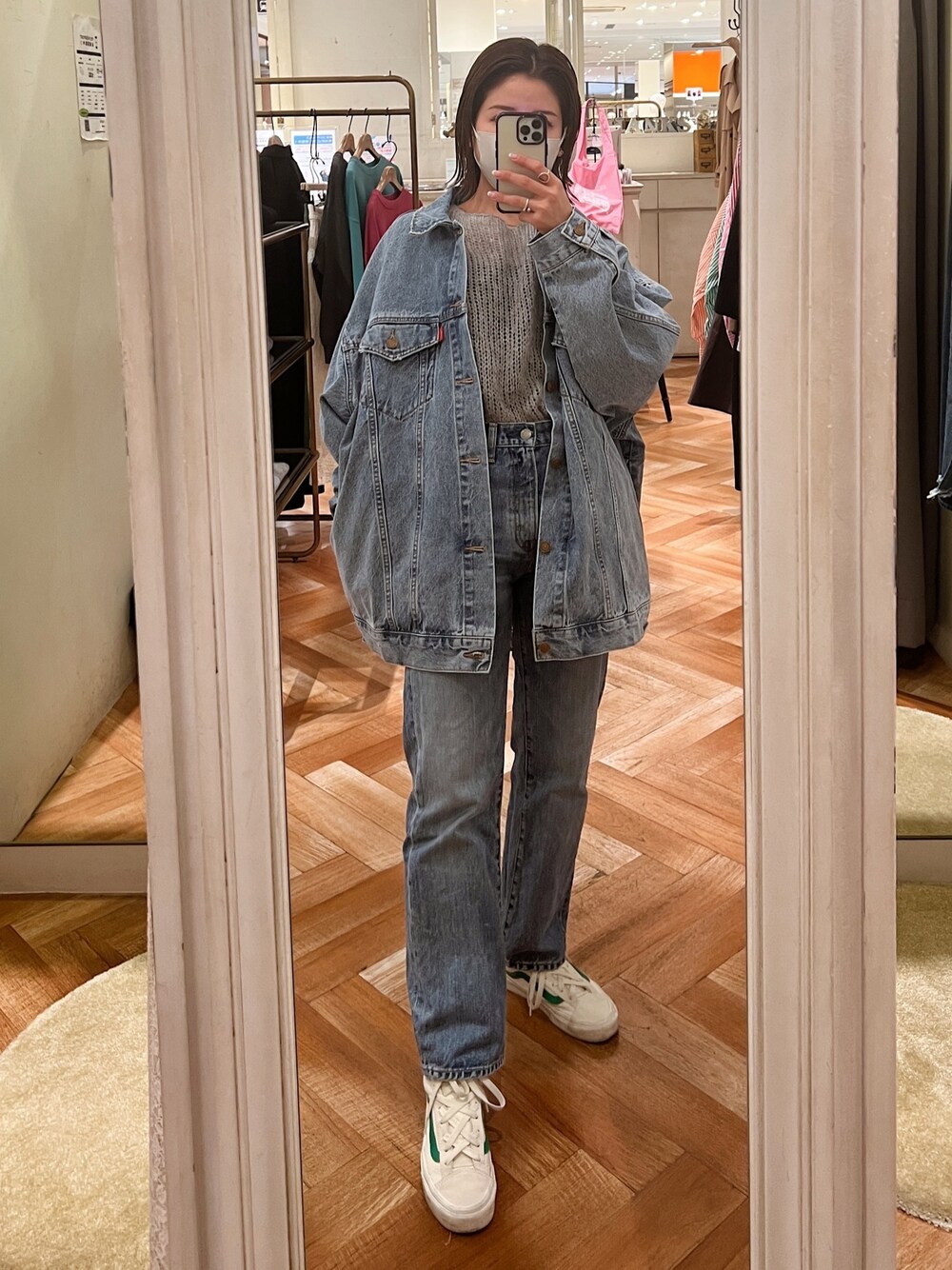 ホワイト系のデニムジャケット、グレー系のニット/セーター、ブルー系のデニムパンツを着用したレディースの冬コーディネートの1枚目の写真