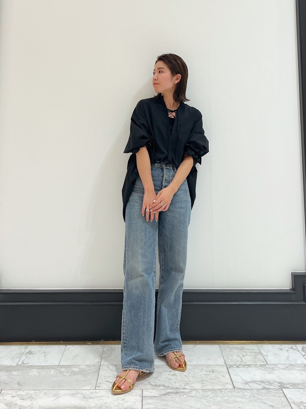ブラック系のシャツ/ブラウス、ブルー系のデニムパンツ、イエロー系のサンダルを着用したレディースの春コーディネートの1枚目の写真