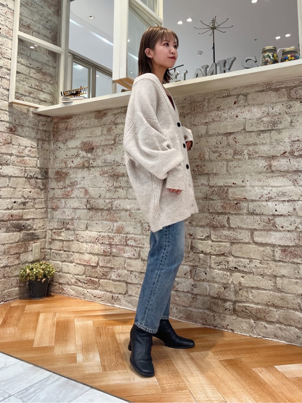 ブラック系のブーツ、ブルー系のデニムパンツ、ホワイト系のカーディガン/ボレロを着用したレディースの秋コーディネートの1枚目の写真