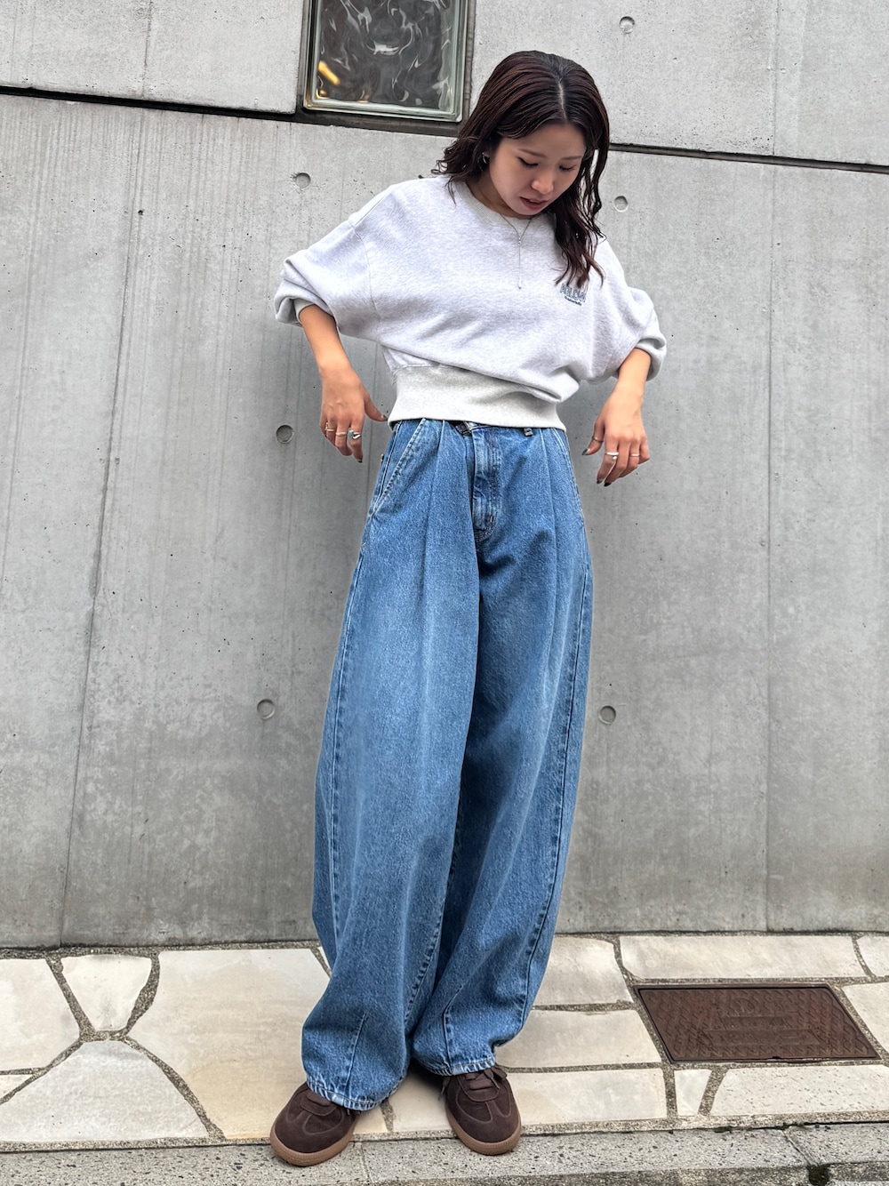 ブルー系のデニムパンツ、グレー系のスウェット、ブラウン系のスニーカーを着用したレディースの秋コーディネートの1枚目の写真