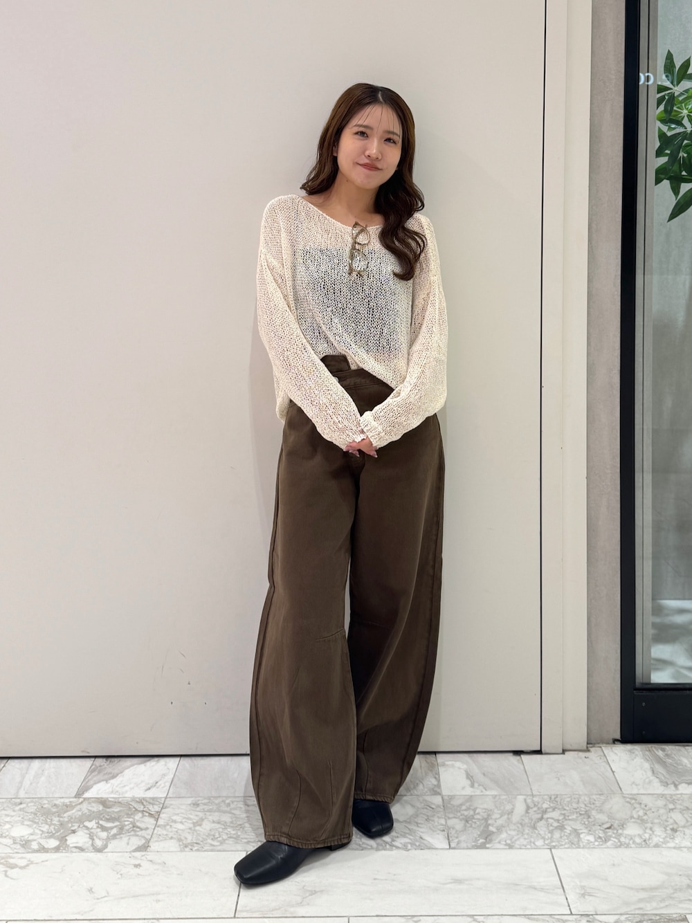 ブラウン系のデニムパンツ、ホワイト系のニット/セーター、ブラック系のサンダルを着用したレディースの秋コーディネートの1枚目の写真