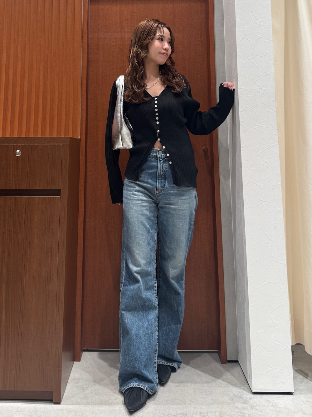 ブルー系のデニムパンツ、ブラック系のカーディガン/ボレロ、ブラック系のパンプスを着用したレディースの春コーディネートの1枚目の写真