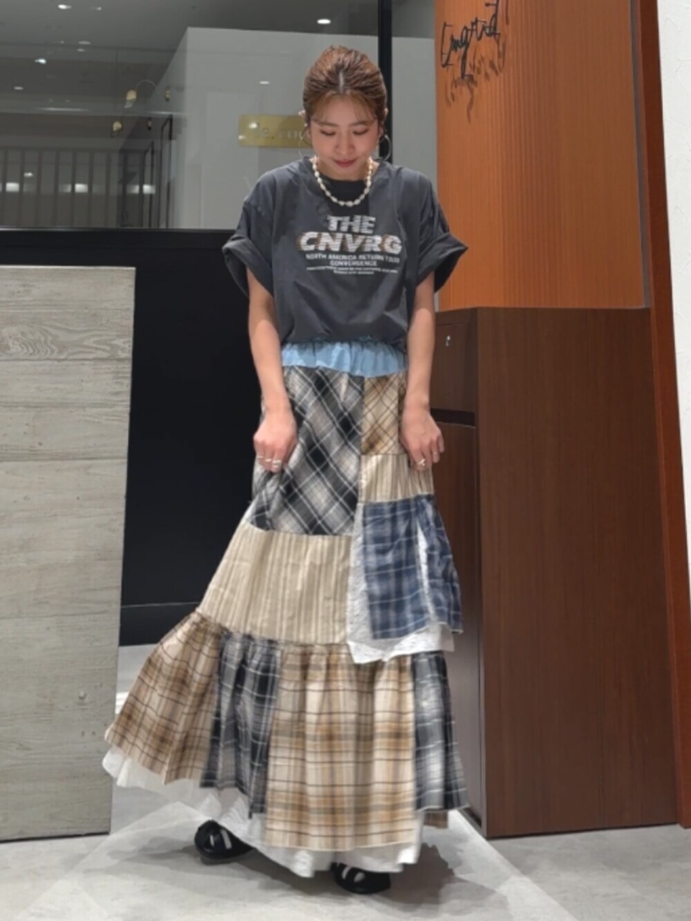 グレー系のTシャツ/カットソー、ブラック系のサンダル、その他のスカートを着用したレディースの春コーディネートの1枚目の写真