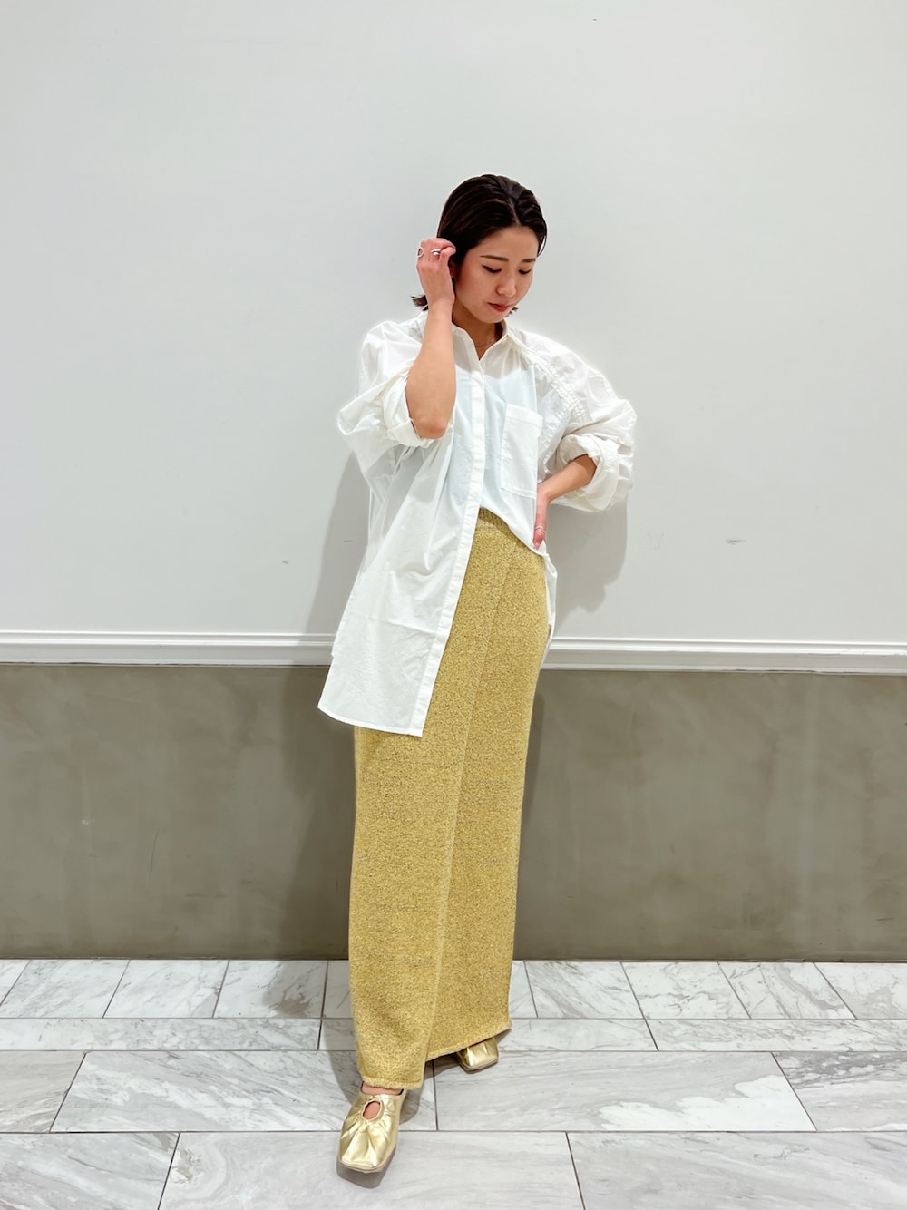 ホワイト系のシャツ/ブラウス、イエロー系のパンプス、ベージュ系のスカートを着用したレディースの冬コーディネートの1枚目の写真