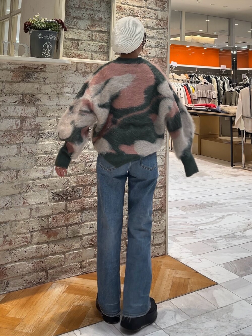 ブラック系のブーツ、グリーン系のニット/セーター、ブルー系のデニムパンツを着用したレディースの秋コーディネートの1枚目の写真