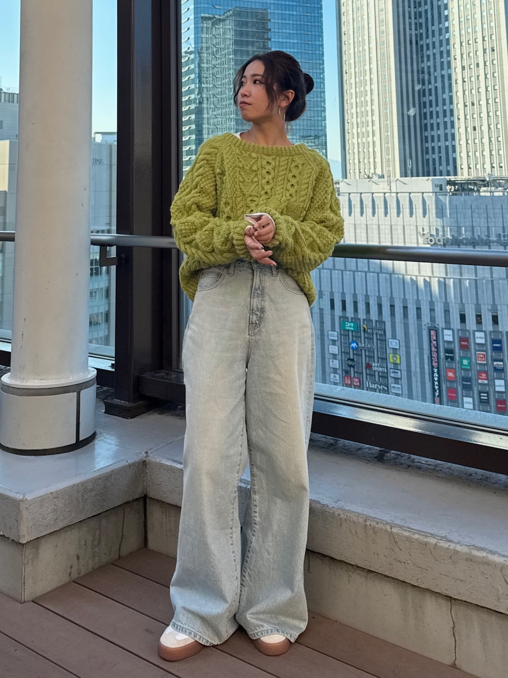 グリーン系のニット/セーター、ホワイト系のTシャツ/カットソー、ブルー系のデニムパンツを着用したレディースの冬コーディネートの1枚目の写真