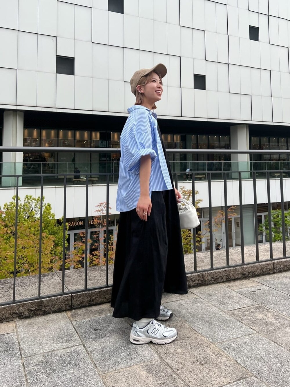 ブラック系のワンピース、ブルー系のシャツ/ブラウス、ホワイト系のハンドバッグを着用したレディースの春コーディネートの1枚目の写真