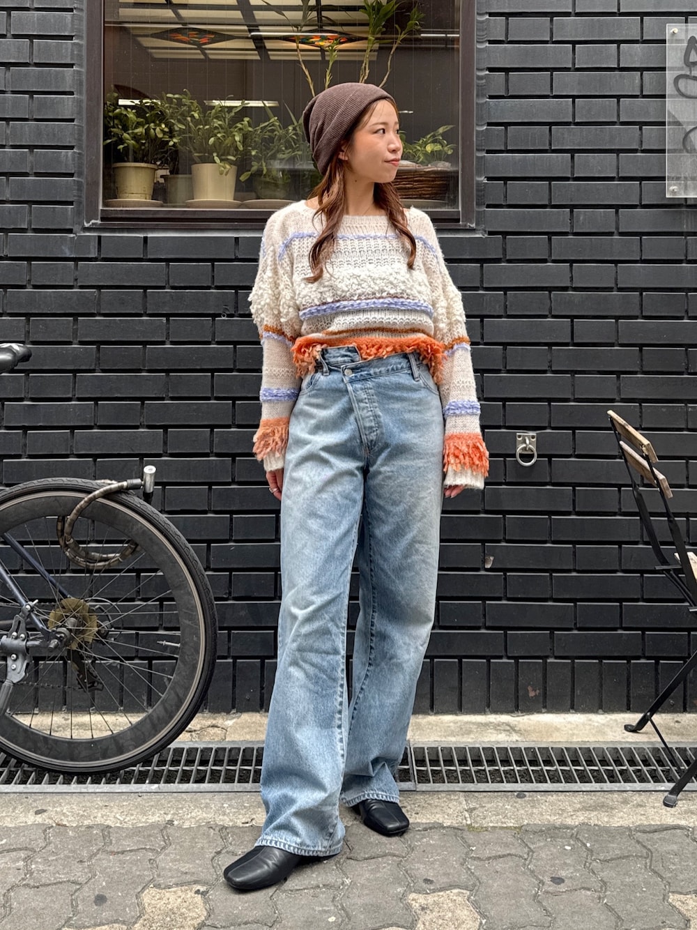 ブルー系のデニムパンツ、ホワイト系のニット/セーター、ブラック系のサンダルを着用したレディースの秋コーディネートの1枚目の写真