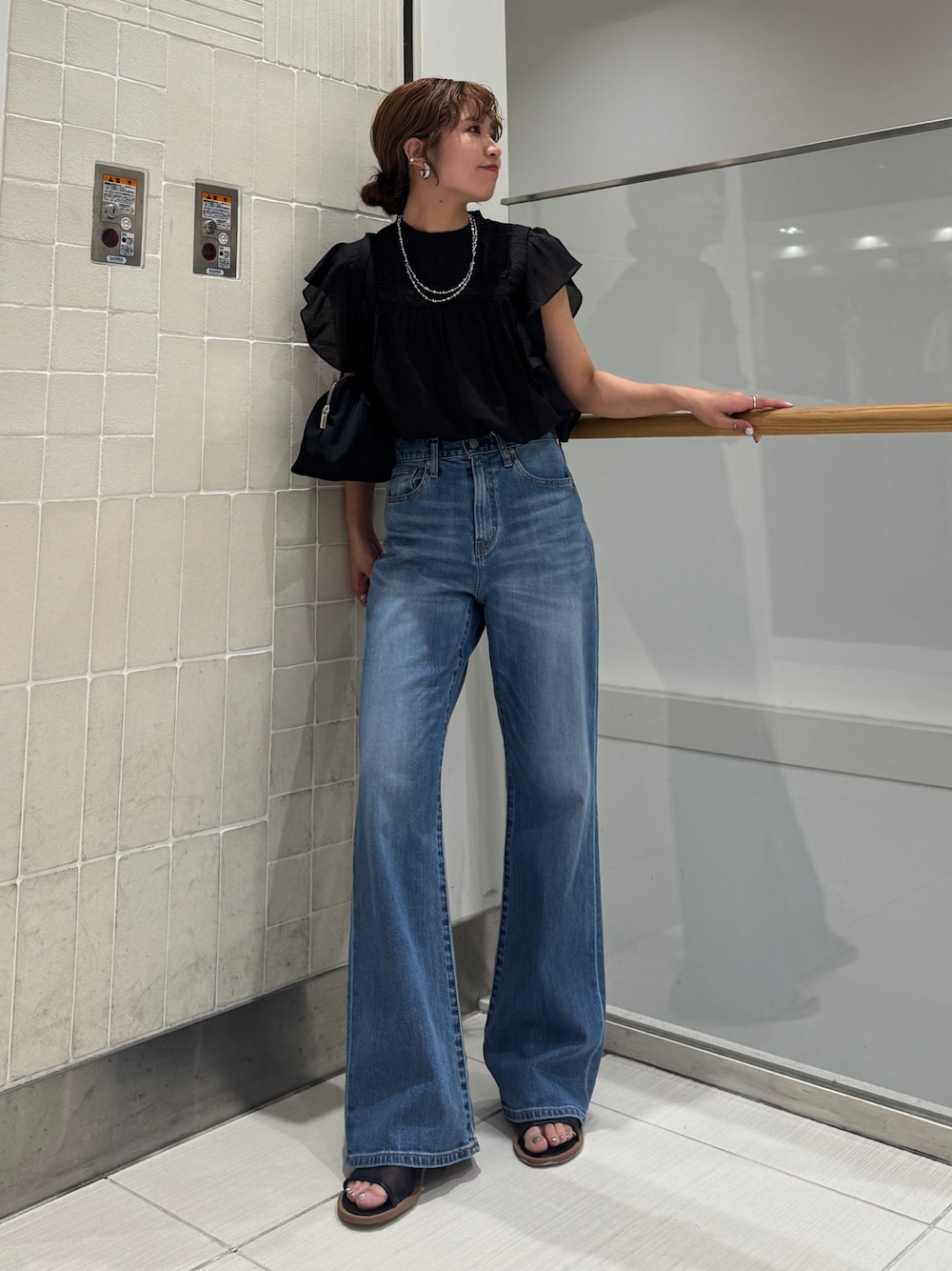 ブルー系のデニムパンツ、ブラック系のシャツ/ブラウス、ブラック系のハンドバッグを着用したレディースの春コーディネートの1枚目の写真