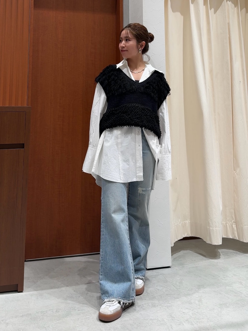 ブラック系のベスト、ホワイト系のシャツ/ブラウス、ブルー系のデニムパンツを着用したレディースの春コーディネートの1枚目の写真