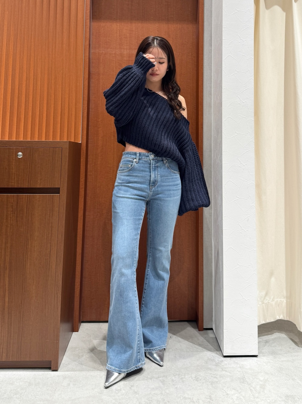 ブルー系のニット/セーター、ブルー系のデニムパンツ、シルバー系のパンプスを着用したレディースの秋コーディネートの1枚目の写真