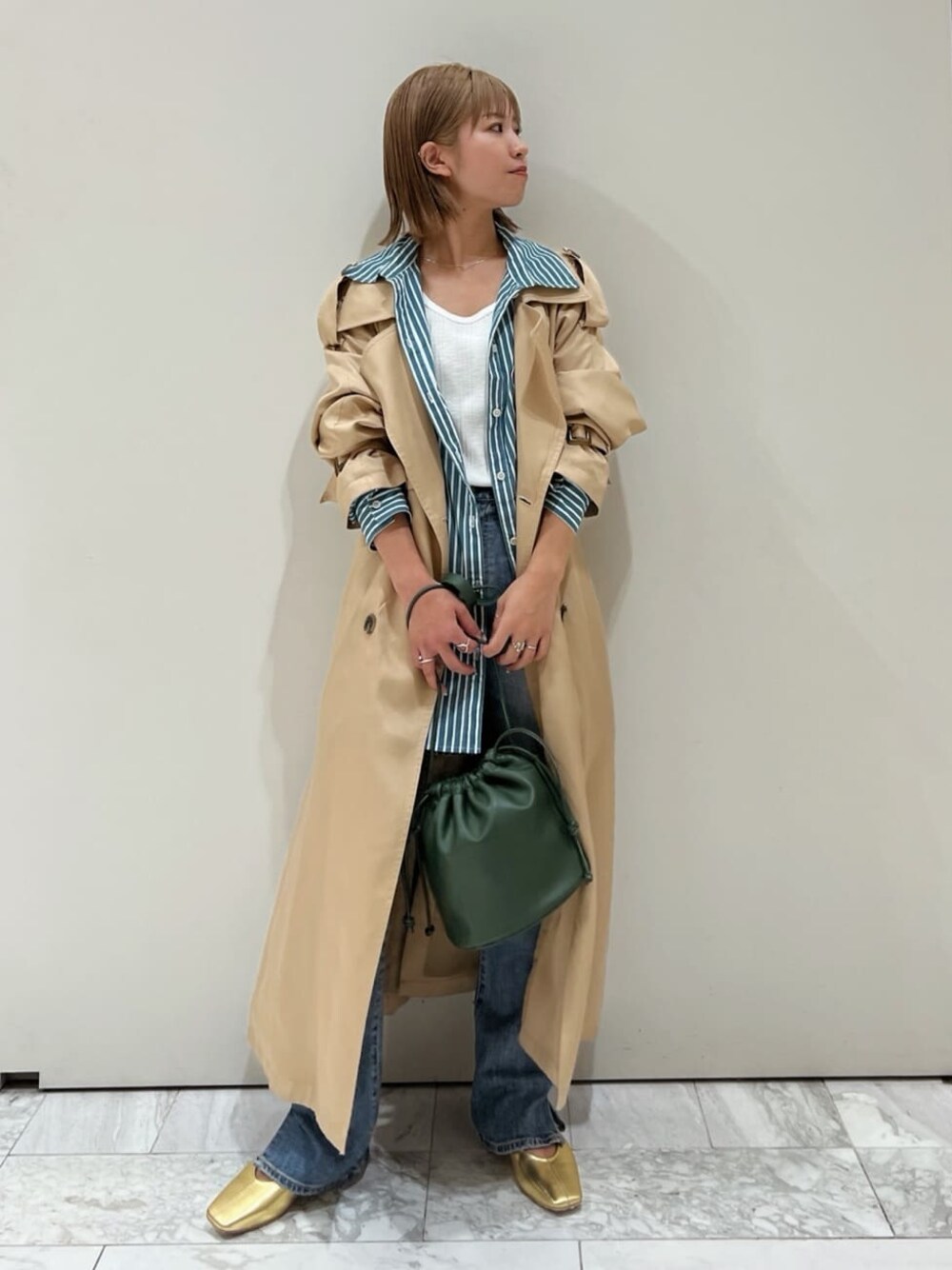 ベージュ系のトレンチコート、グリーン系のシャツ/ブラウス、ブルー系のデニムパンツを着用したレディースの夏コーディネートの1枚目の写真