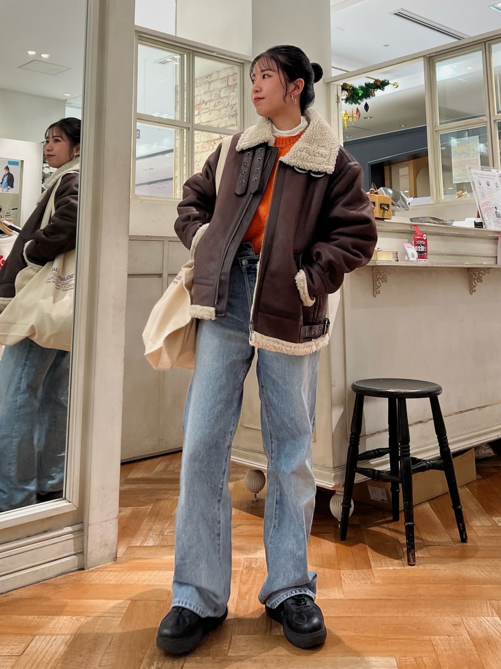 オレンジ系のニット/セーター、ホワイト系のTシャツ/カットソー、ブルー系のデニムパンツを着用したレディースの冬コーディネートの1枚目の写真