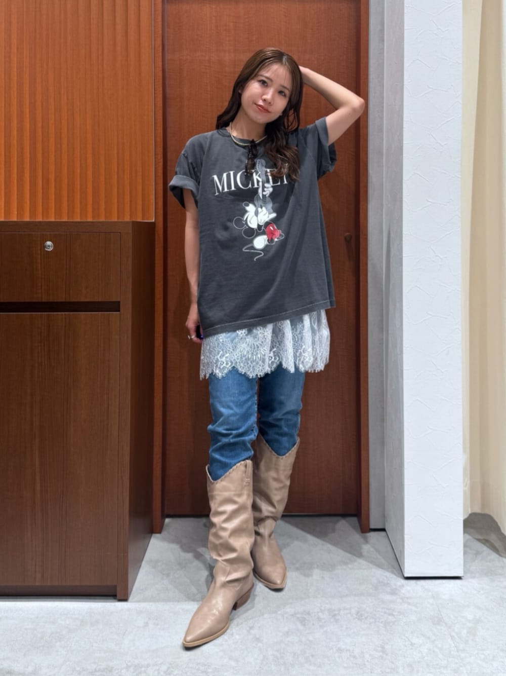 ベージュ系のブーツ、ブルー系のデニムパンツ、ホワイト系のキャミソールを着用したレディースの夏コーディネートの1枚目の写真