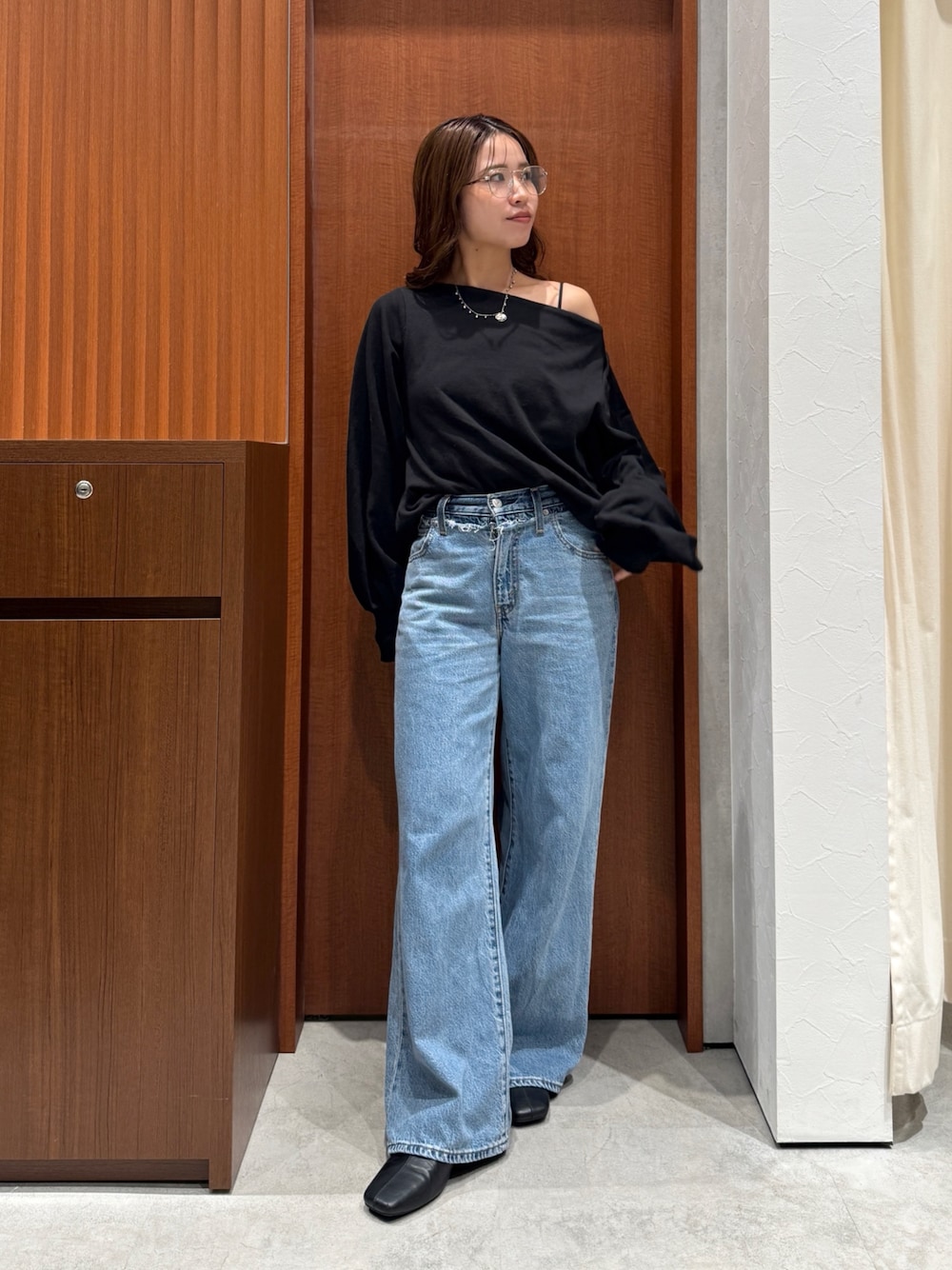 ブルー系のデニムパンツ、ブラック系のスウェット、シルバー系のメガネを着用したレディースの秋コーディネートの1枚目の写真